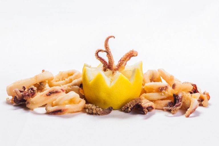 Calamar frito dentro de un limón rodeado de calamares fritos