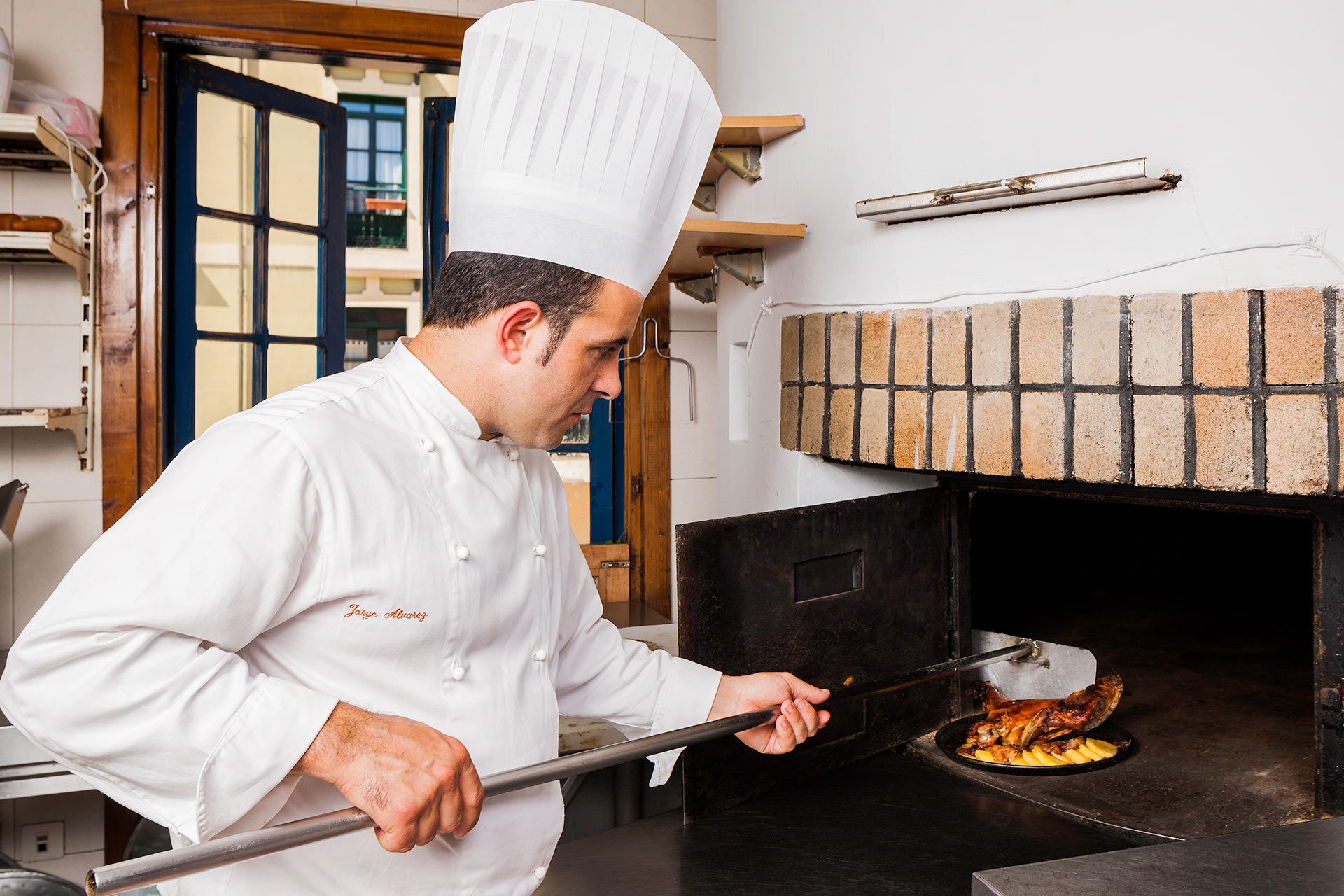 Cocinero elaborando cordero lechal al horno en Casa Ramón Oviedo